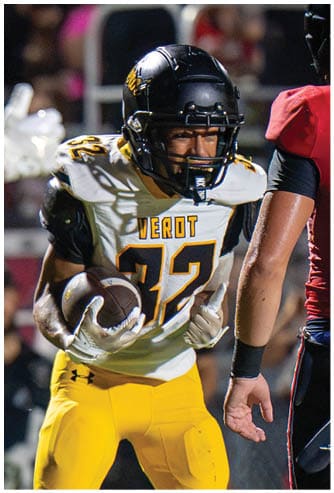 A person wearing a black football helmet and a white jersey with the number 32 and the word “VEROT" is engaged in a football game next to another person in a red and black uniform. Descripci n generada con IA