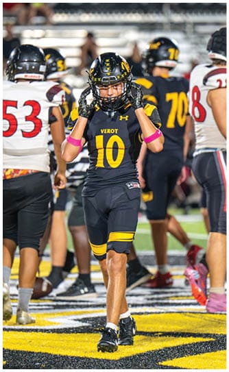 A person wearing a black and yellow football uniform with the number 10 is walking on a field with other players in the background. Descripci n generada con IA