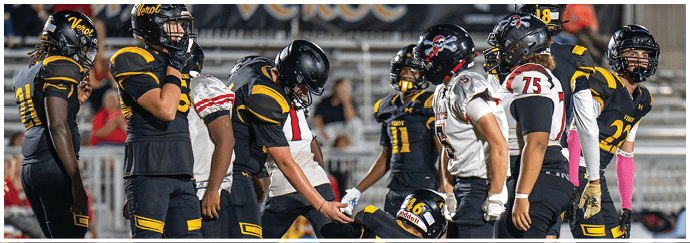 Football players in uniforms are on the field with one player helping another player up while others stand nearby. Descripci n generada con IA