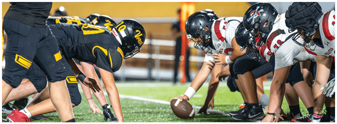 Two opposing American football teams in black and white uniforms are lined up facing each other on the field, ready for the next play. Descripci n generada con IA