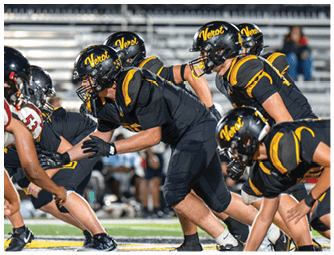Several people in black and yellow football uniforms are lined up on a field, preparing for a play against opponents in white and red uniforms. Descripci n generada con IA
