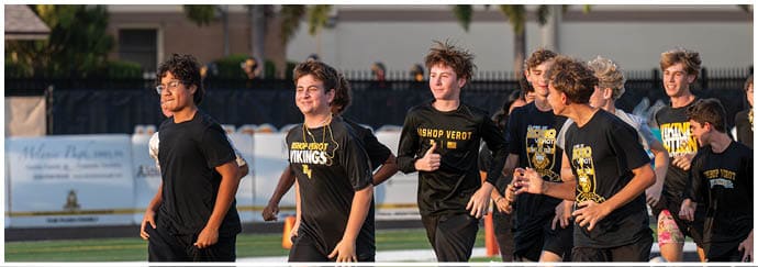 A group of people wearing black sports shirts are jogging together outdoors on a field. Descripci n generada con IA