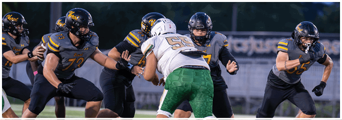Several people wearing football uniforms are engaged in a play on a field, with one person in white and green facing opponents in dark uniforms. Descripci n generada con IA