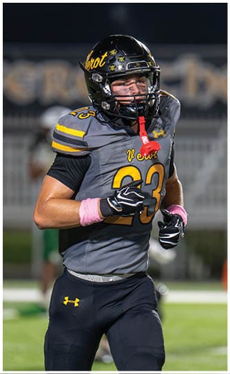 A person wearing a black and gray football uniform with the number 33 is running on a football field at night. Descripci n generada con IA