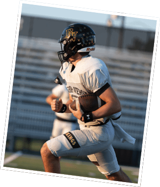 A person wearing a football uniform and helmet is running on a field while holding a football. Descripci n generada con IA