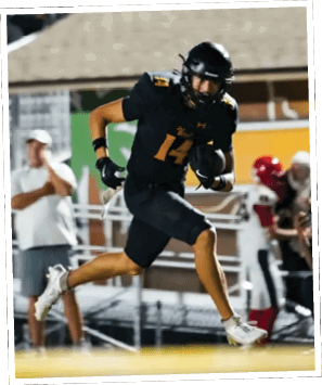 A person wearing a black football uniform with the number 14 is running on a field while holding a football, with other people and players in the background. Descripci n generada con IA