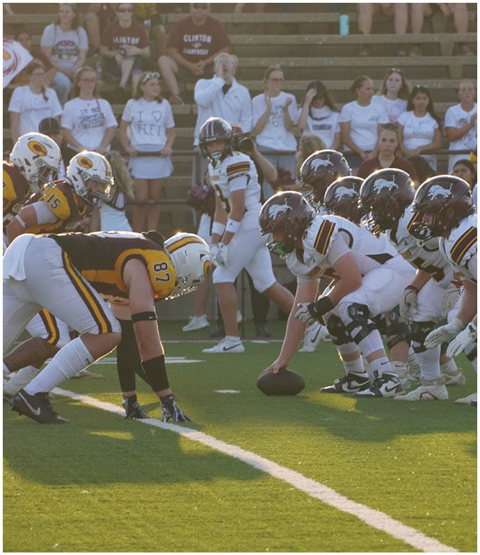 Three football players in blue and white uniforms running on a field. Description generated by AI