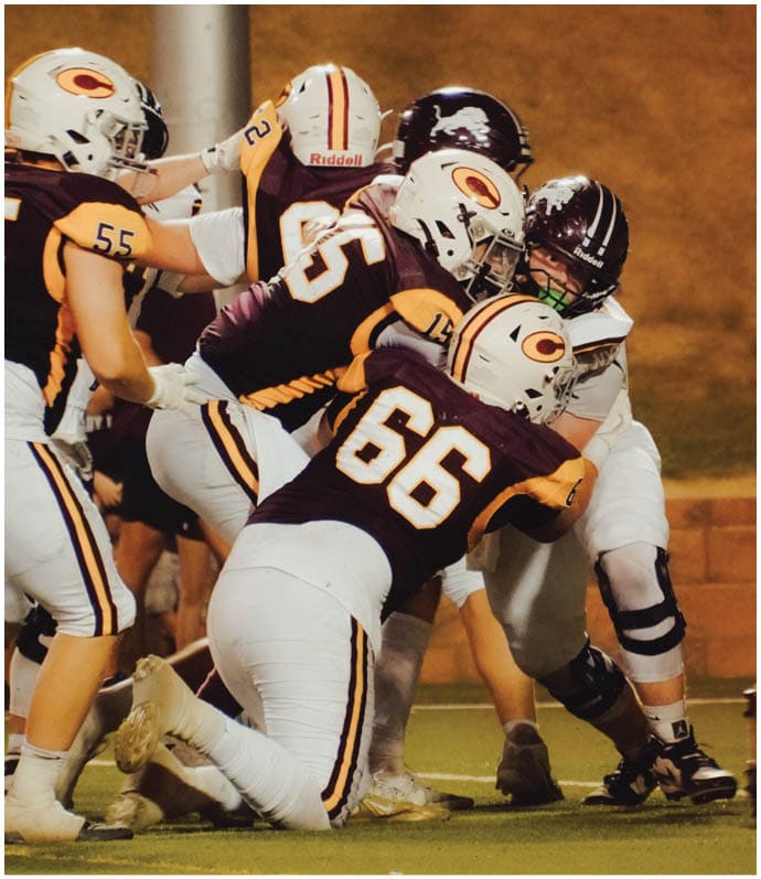 Three football players in blue and white uniforms running on a field. Description generated by AI