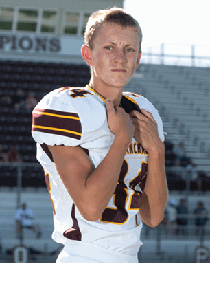 A young man wearing a white and black jersey with the number 14 on it. Description generated by AI