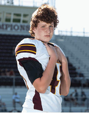 A young man wearing a white and black jersey with the number 14 on it. Description generated by AI