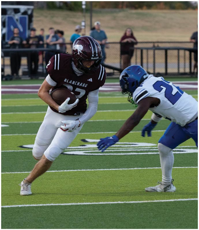 Three football players in blue and white uniforms running on a field. Description generated by AI