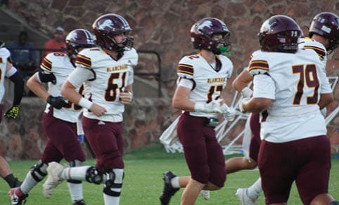 Two men wearing football uniforms are hugging each other on a field. AI generated content