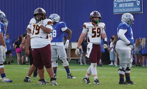 Two men wearing football uniforms are hugging each other on a field. AI generated content