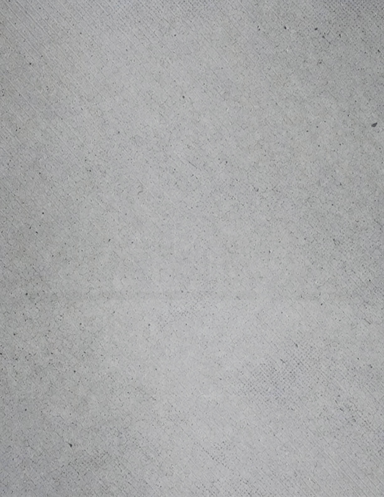 A close-up view of a textured gray surface with subtle diagonal lines and small scattered dark specks. Description generated by AI