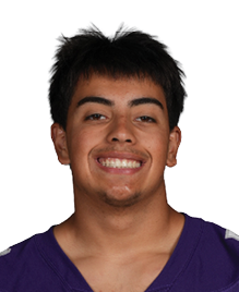 A person with short dark hair is smiling and wearing a purple football jersey with the number 58 and the word Bloomington on the front. Description generated by AI
