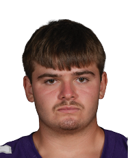 Person wearing a purple Bloomington football jersey with the number 64 stands facing forward with hands behind their back. Description generated by AI