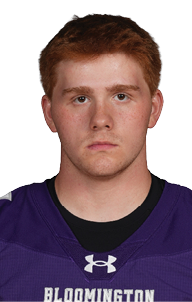 Person with short hair wearing a purple Bloomington sports jersey with the number 61 standing against a white background. Description generated by AI