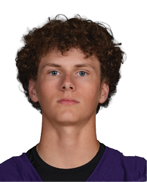 A person with curly hair wearing a purple Bloomington sports jersey with the number 3 stands against a white background. Description generated by AI
