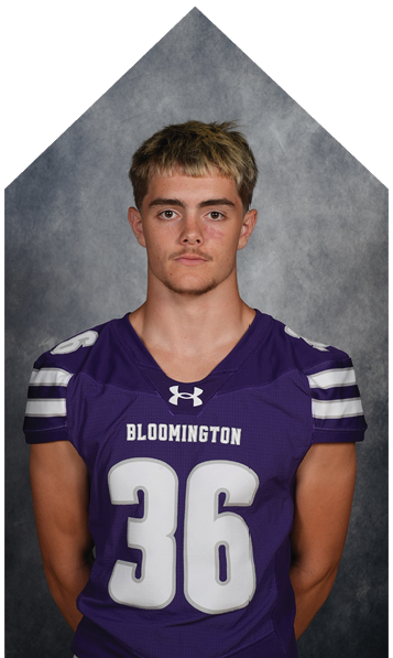 Person with short hair wearing a purple Bloomington sports jersey with white stripes on the sleeves against a gray background. Description generated by AI