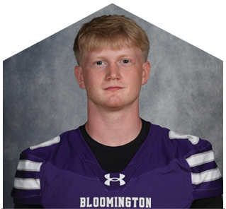 A person with short light hair wearing a purple sports jersey with the word Bloomington on the front is posing against a gray background. Description generated by AI