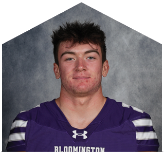 Person wearing a purple Bloomington sports jersey with the number 87 standing against a gray background. Description generated by AI