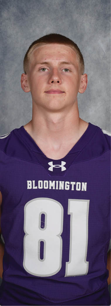 A person wearing a purple sports jersey with the number 81 and the word Bloomington stands against a gray textured background. Description generated by AI