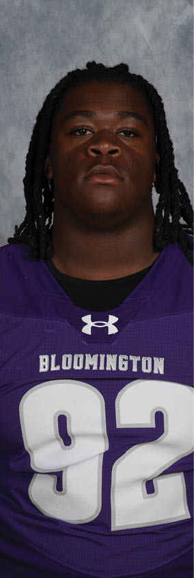 Person wearing a purple sports jersey with the number 92 and the word Bloomington on it against a gray background. Description generated by AI