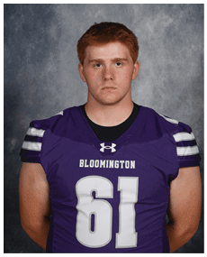 A person with short hair wearing a purple Bloomington football jersey with the number 61 stands against a gray textured background with a neutral expression. Description generated by AI