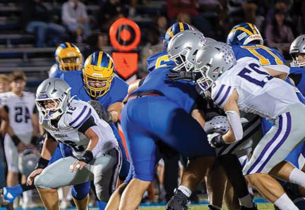 A group of people wearing football helmets and uniforms are engaged in a play on a football field during a game. Description generated by AI