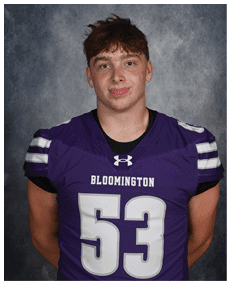 A person with short tousled hair wearing a purple Bloomington sports jersey with the number 53 stands against a gray mottled background. Description generated by AI