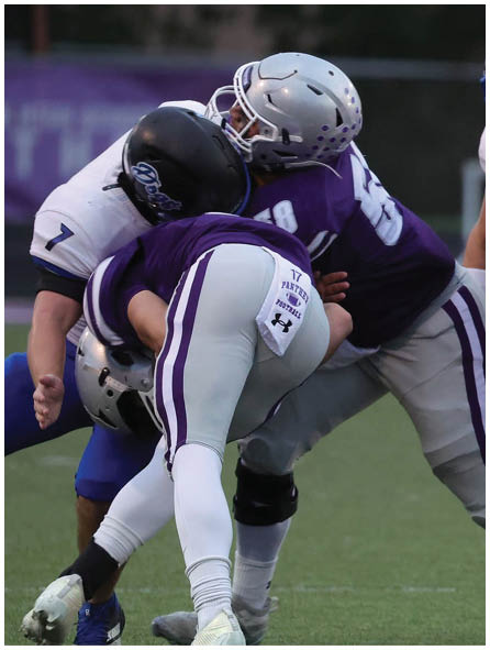 Several people wearing football uniforms are engaged in a close physical play on a grassy field. Description generated by AI