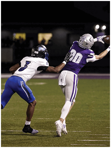Two people wearing athletic clothing are running on a grassy field near a sideline. Description generated by AI