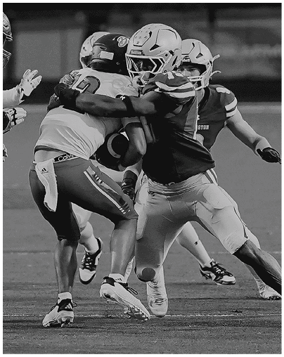 Two people in football uniforms are engaged in a tackle on a grassy field during a game. Description generated by AI