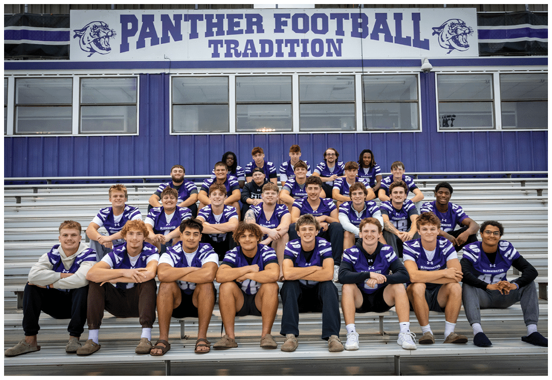 A group of people wearing matching purple and white sports jerseys are seated on bleachers under a sign that reads “Panther Football Tradition." Description generated by AI