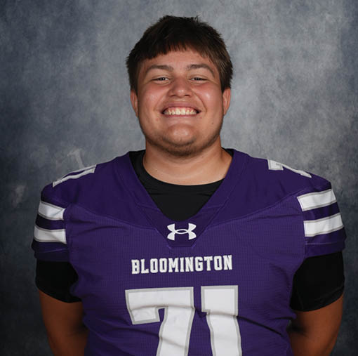 A person wearing a purple Bloomington football jersey with the number 71 is smiling against a gray textured background. Description generated by AI