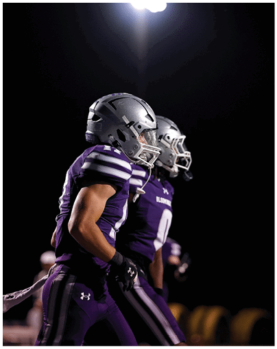 A bright stadium light illuminates the dark sky above two sports helmets. Description generated by AI