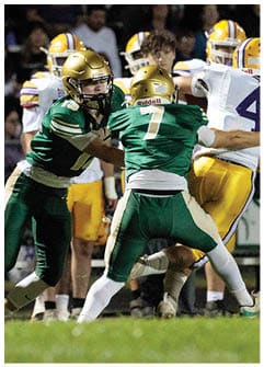 A person in a green football uniform is tackling another person in a white and yellow football uniform during a game. Description generated by AI