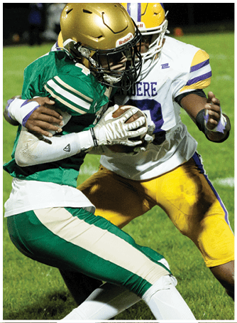 Two football players in helmets and white jerseys are closely engaged during a game, with one holding a football. Description generated by AI