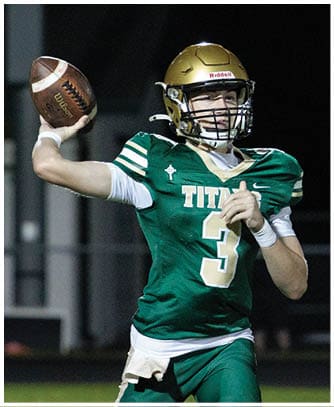 A person wearing a green football uniform with the number 3 and a gold helmet is running on a field at night. Description generated by AI