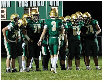 People wearing green and gold football uniforms with numbers 78, 3, and 50 standing closely together on a field. Description generated by AI