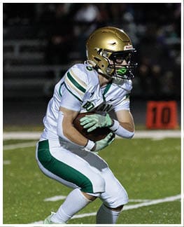 A person wearing a gold helmet and white sports uniform is running on a green field near an orange marker with the number 10. Description generated by AI