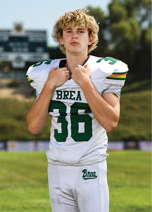 A young man wearing a white and black jersey with the number 14 on it. Description generated by AI