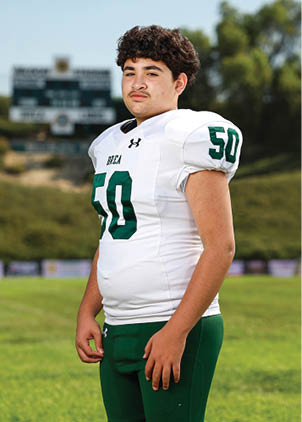 A young man wearing a white and black jersey with the number 14 on it. Description generated by AI