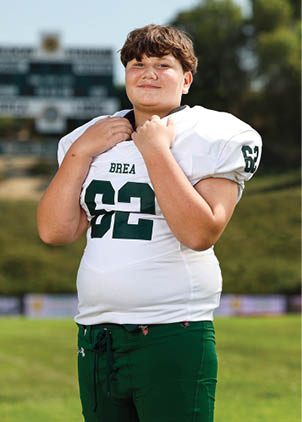 A young man wearing a white and black jersey with the number 14 on it. Description generated by AI