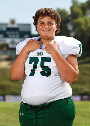 A young man wearing a white and black jersey with the number 14 on it. Description generated by AI