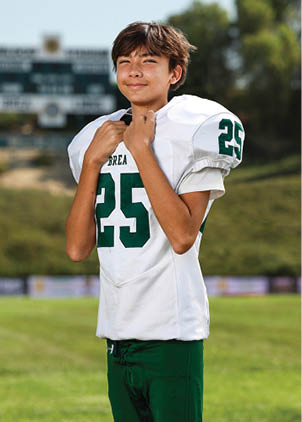 A young man wearing a white and black jersey with the number 14 on it. Description generated by AI