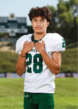 A young man wearing a white and black jersey with the number 14 on it. Description generated by AI