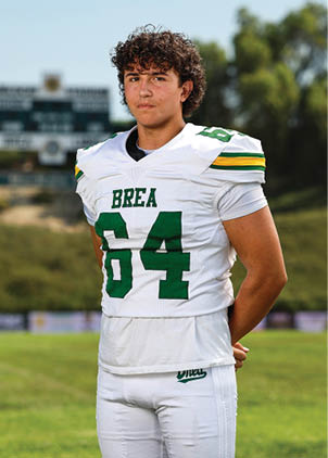 A young man wearing a white and black jersey with the number 14 on it. Description generated by AI