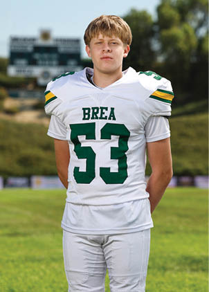 A young man wearing a white and black jersey with the number 14 on it. Description generated by AI