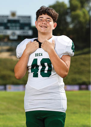 A young man wearing a white and black jersey with the number 14 on it. Description generated by AI